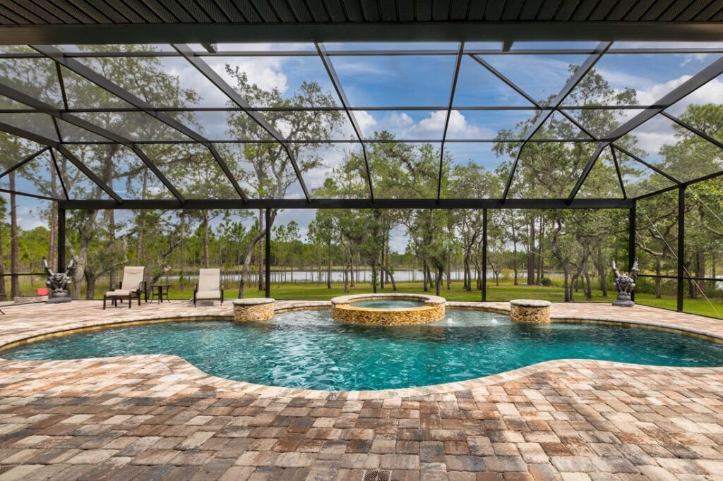 Newberry_house_pool free form pool with integrated whirlpool spa covered shown inside spacious screen enclosure