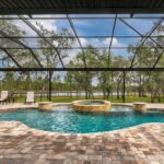 free form pool with integrated whirlpool spa covered shown inside spacious screen enclosure