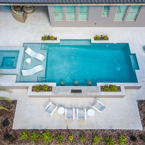 overhead view of luxury pool with wading deck and whirlpool spa and outdoor seating nearby