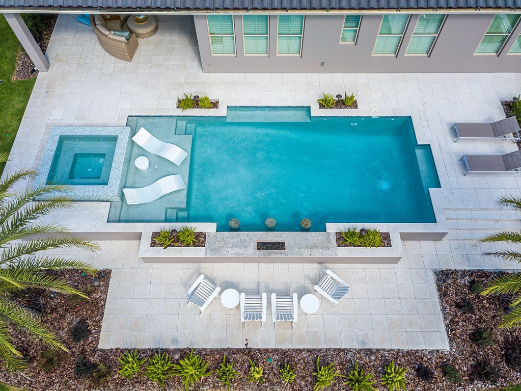 overhead view of luxury pool with wading deck and whirlpool spa and outdoor seating nearby
