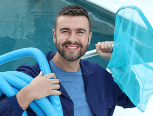 pool maintenance worker stands near pool while holding pool cleaning equipment