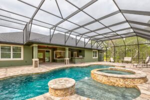 pool with integrated spa inside screen enlosure attached to a residential home