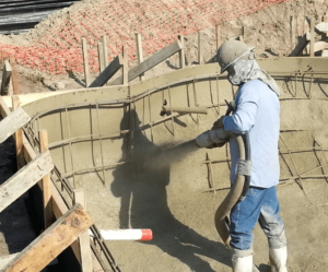 worker spraying gunite to build shell of a new pool