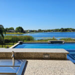 covered outdoor sink and single handle faucet installed in outdoor kitchen with view of luxury pool and lake
