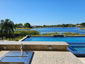 covered outdoor sink and single handle faucet installed in outdoor kitchen with view of luxury pool and lake
