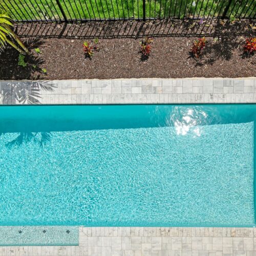 long rectangular pool with side to side stairs leading up to natural stone pattern deck