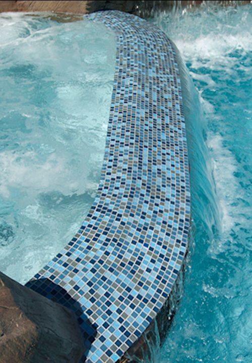 water flows over tiled ledge in a waterfall from a whirlpool to a pool
